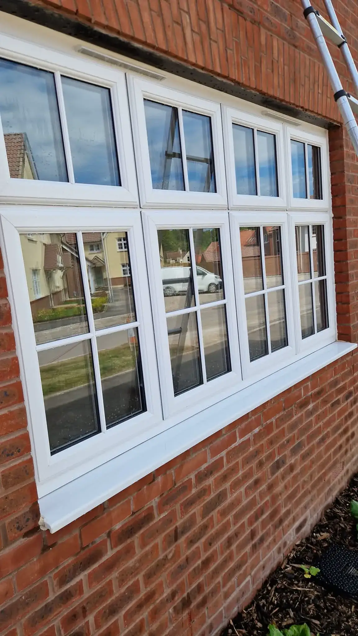 Sparkling clean white UPVC windows on a red brick house after professional cleaning